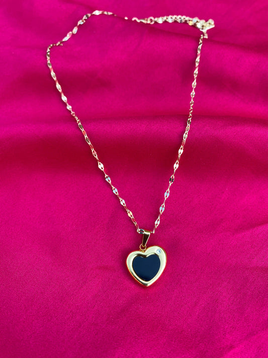 Necklace with a heart-shaped black pendant on a pink background
