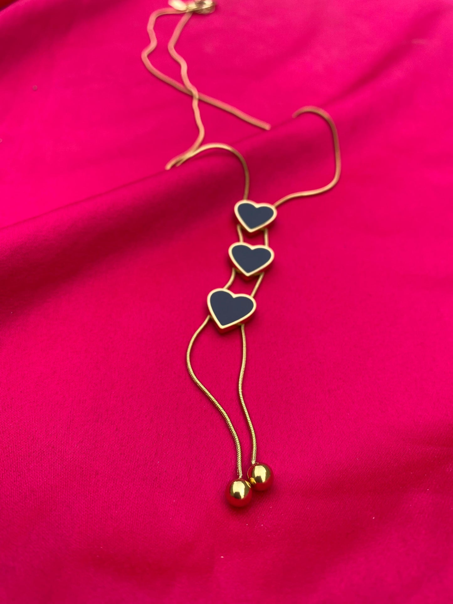 Necklace with heart-shaped pendants on a pink fabric background