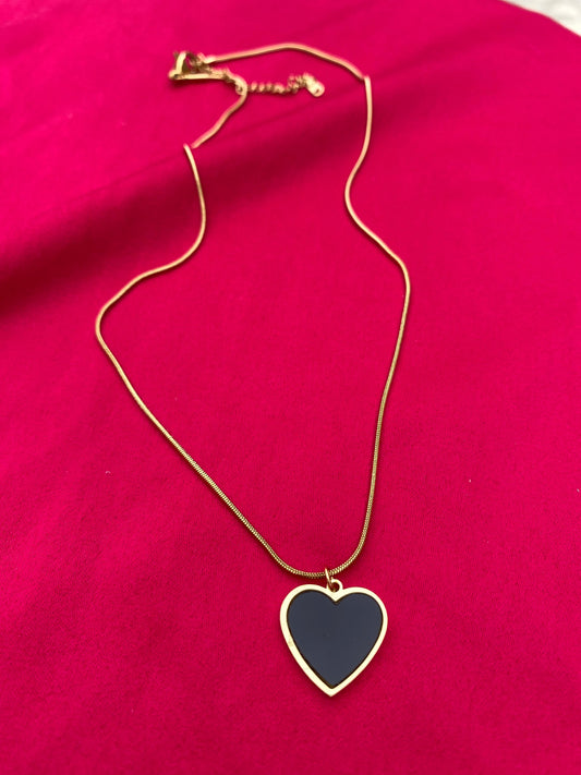 Gold necklace with a heart-shaped pendant on a pink background