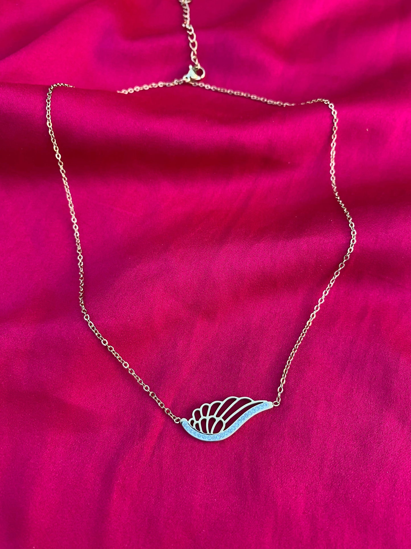 Necklace with a leaf-shaped pendant on a pink fabric background