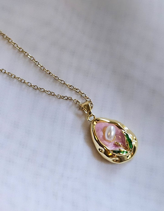 Modern Gold Drop Necklace with Pearl Detail on a Pink Background