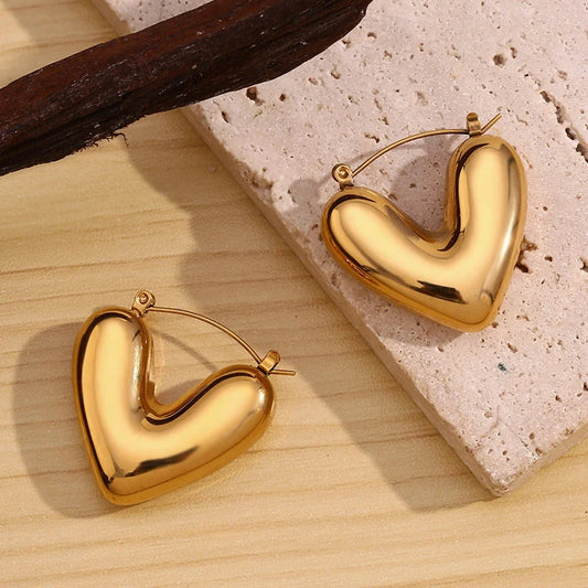 Chunky gold heart hoop earrings on stone surface