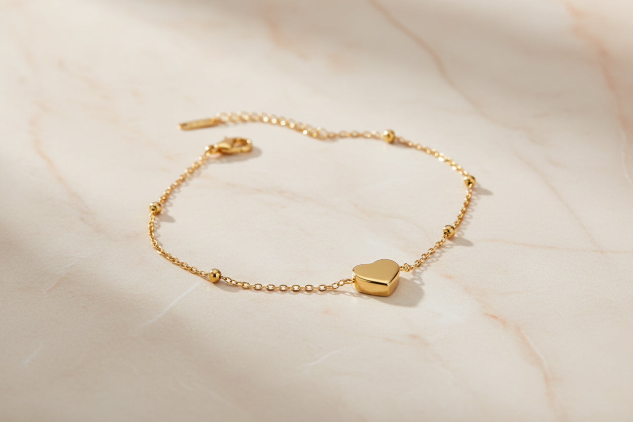 Gold bracelet with heart-shaped charms on a beige surface