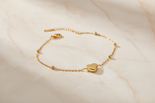 Gold bracelet with heart-shaped charms on a beige surface