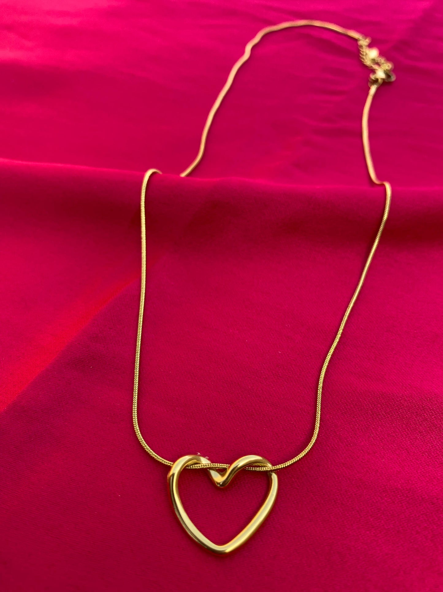 Gold heart-shaped necklace on a red fabric background