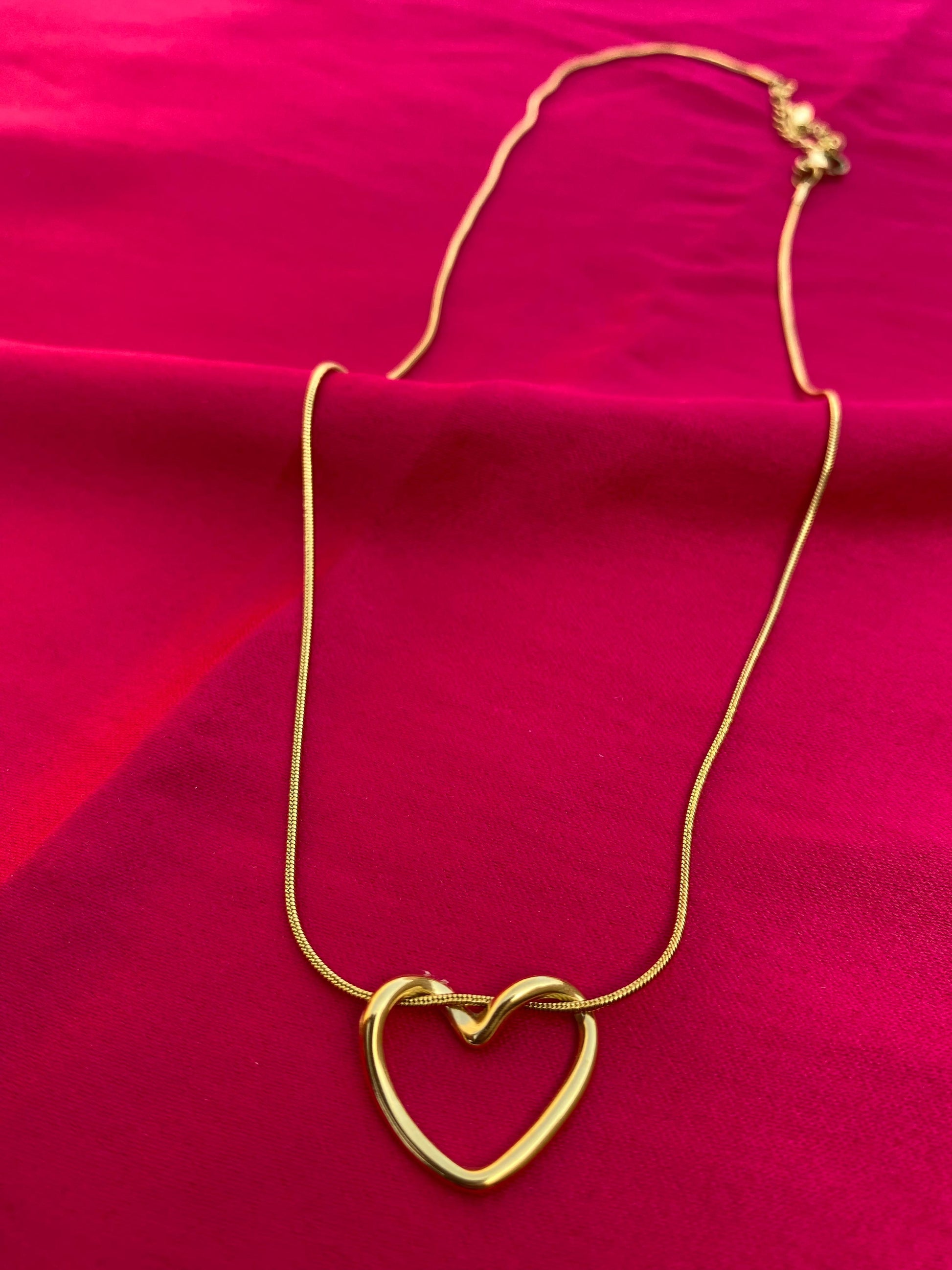 Gold heart-shaped necklace on a red fabric background