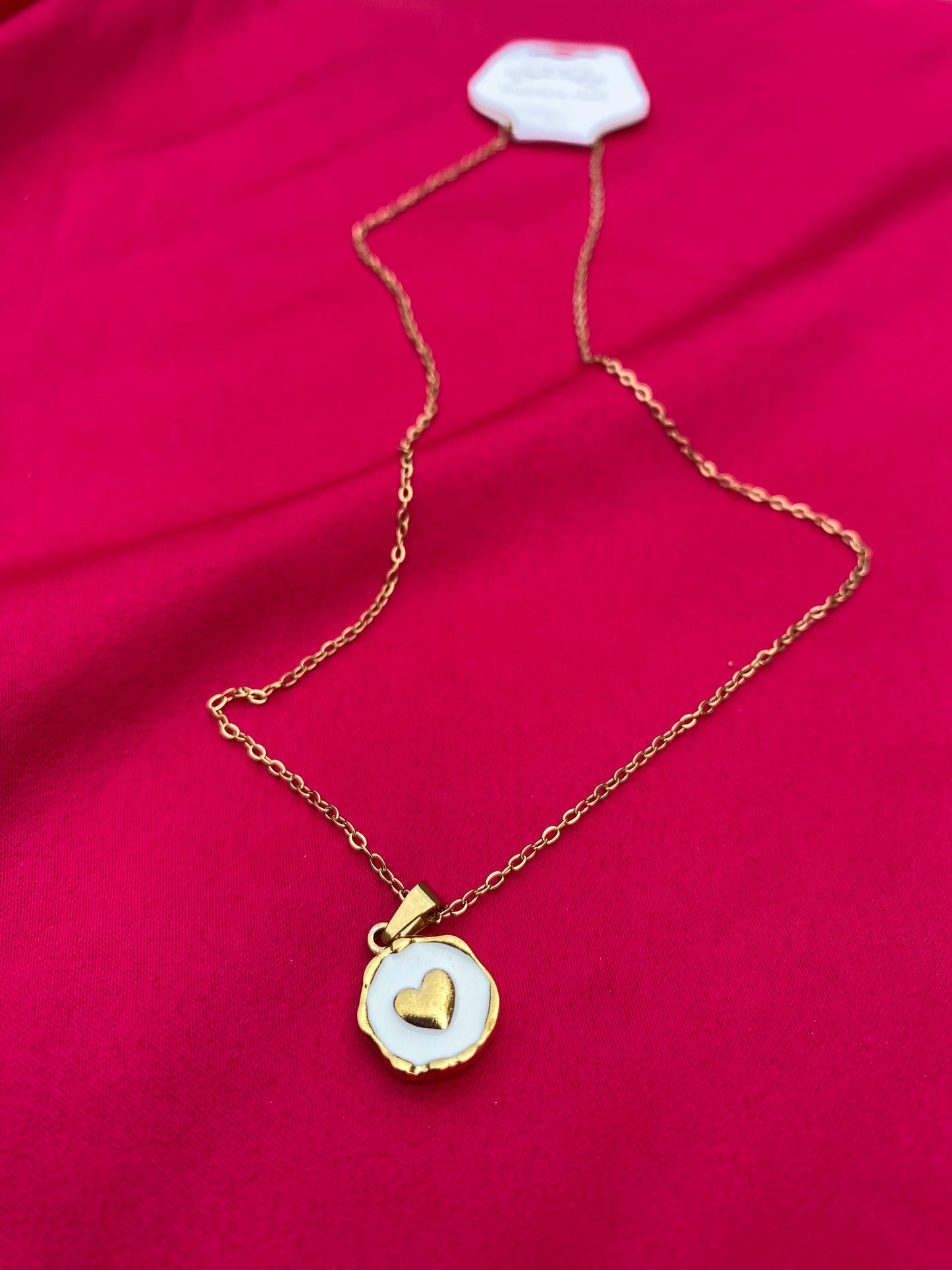 Gold necklace with a heart pendant on a red fabric background
