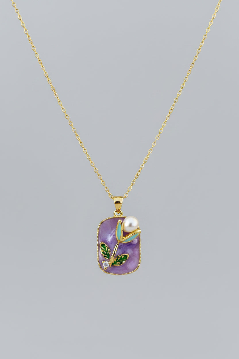 Gold necklace with a purple pendant featuring a pearl 