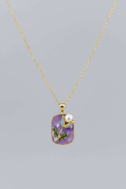 Gold necklace with a purple pendant featuring a pearl 