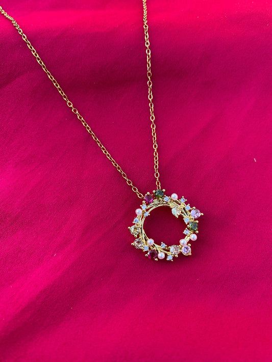 Necklace with a circular pendant featuring colorful stones on a pink background