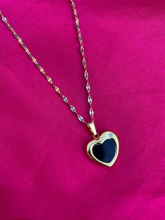 Heart-shaped pendant necklace with blue stone on a pink fabric background