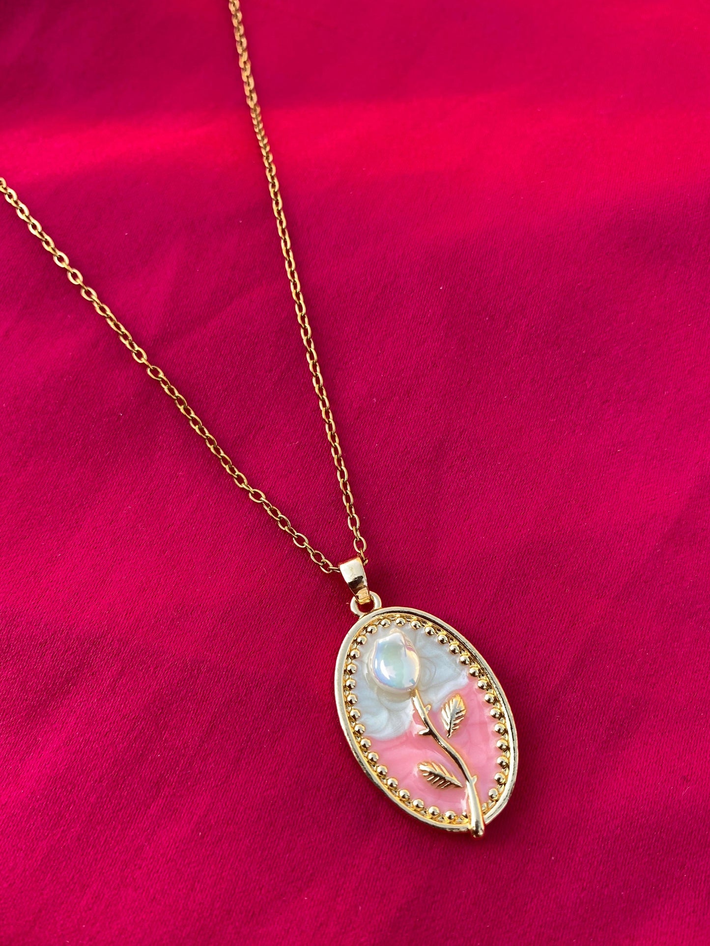 Gold necklace with a decorative pendant on a red fabric background