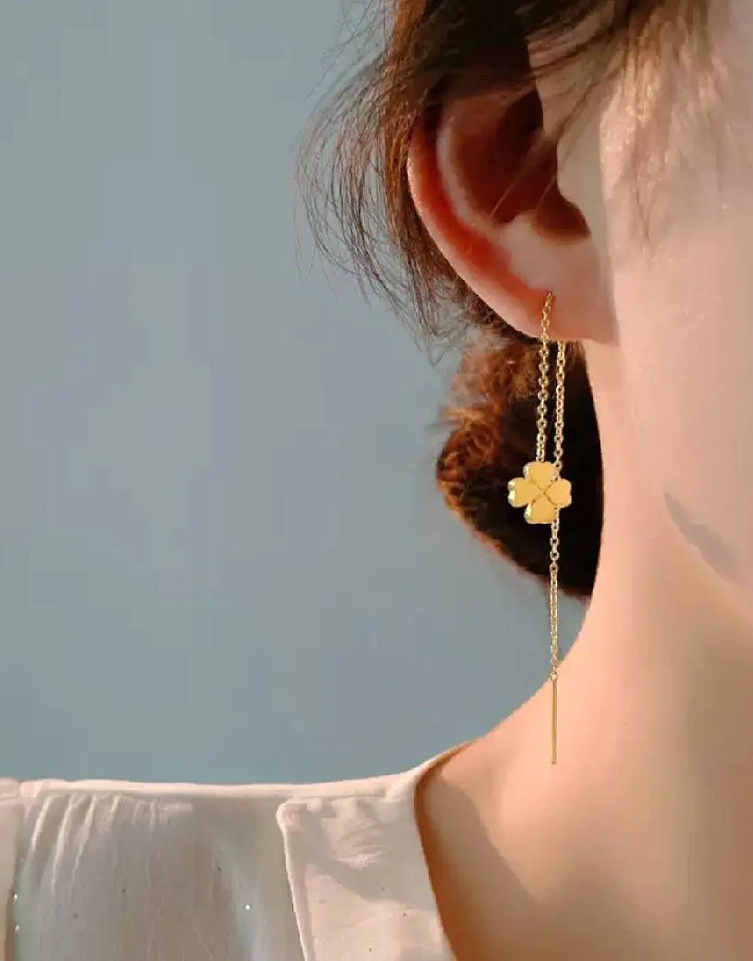Gold clover threader drop earrings worn on model ear